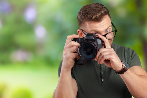 Retrato de un joven guapo en gafas hombre con cámara