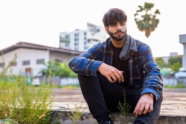 Retrato de joven guapo hipster indio barbudo en las calles de la ciudad al aire libre