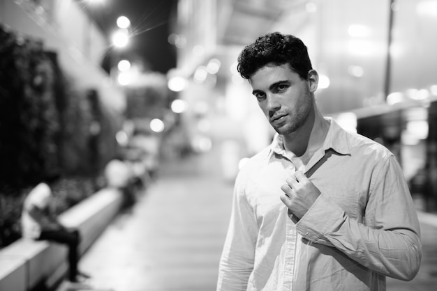 Retrato de joven guapo hispano explorando las calles de la ciudad por la noche