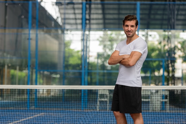 Retrato de joven guapo hispano listo para jugar en la pista de pádel