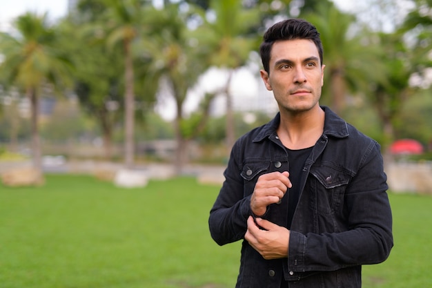 Retrato de joven guapo hispano en el parque al aire libre