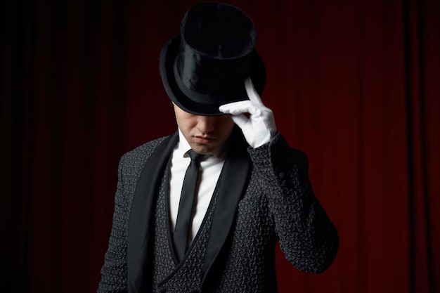 Retrato de un joven y guapo ilusionista tocando el borde del sombrero