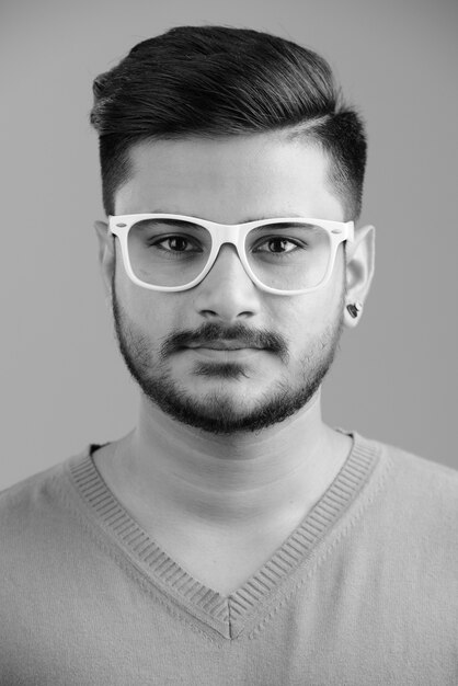 Retrato de joven guapo indio barbudo en blanco en blanco y negro