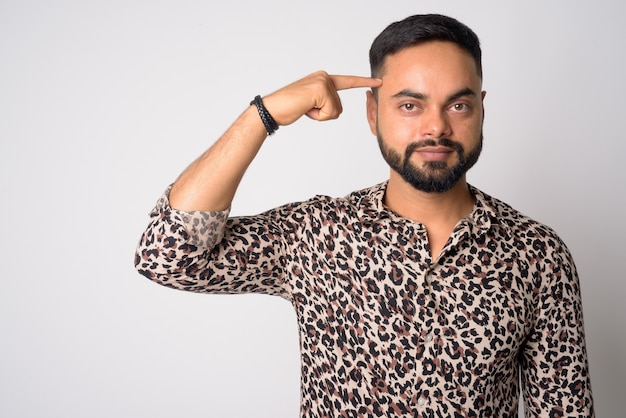 Retrato de joven guapo indio barbudo contra la pared blanca