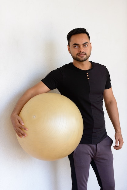 Retrato de joven guapo indio barbudo haciendo ejercicio en el gimnasio