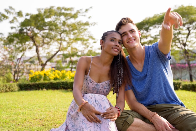 Retrato de joven guapo y joven bella mujer asiática relajándose juntos en el parque