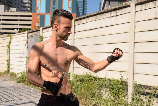 Retrato de joven guapo luchador con cuerpo musculoso magro al aire libre con six pack abs