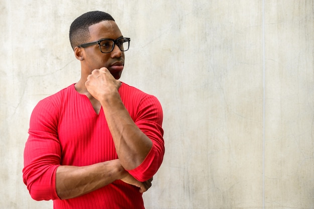 Retrato de joven guapo musculoso africano con anteojos contra el muro de hormigón al aire libre