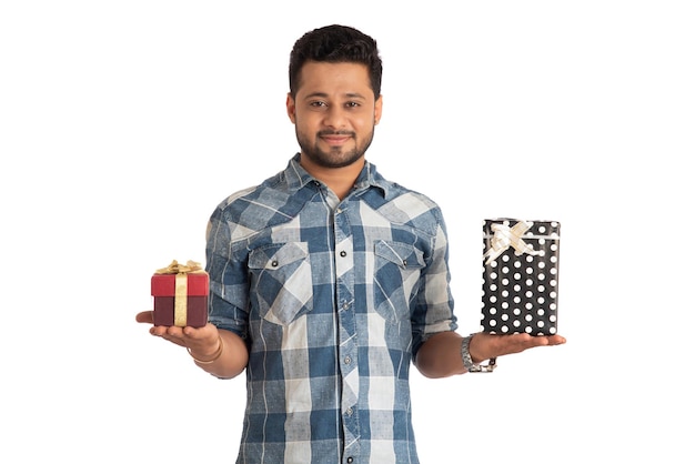 Retrato de un joven guapo sonriente feliz sosteniendo una caja de regalo y posando sobre un fondo blanco