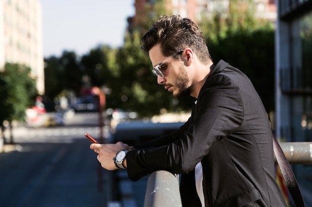 Retrato de joven guapo con su teléfono móvil en la calle.