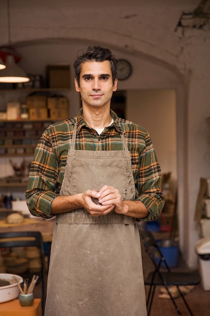 Retrato de joven guapo en taller de cerámica con arcilla