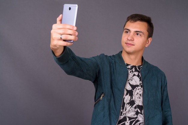 Retrato de joven guapo tomando selfie con teléfono móvil