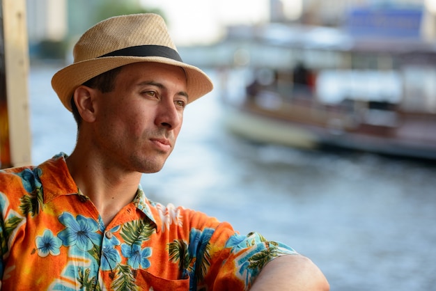 Retrato de joven guapo turista montando en barco como transporte público en la ciudad de Bangkok