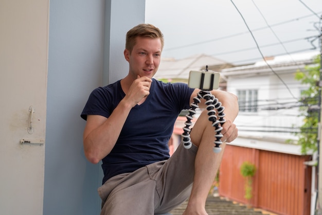 Retrato de joven guapo vlogging en casa