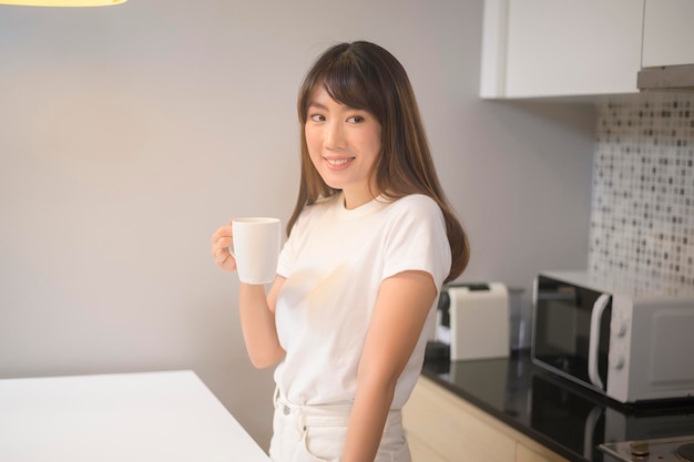 Un retrato de una joven hermosa bebiendo un vaso de agua en la cocina