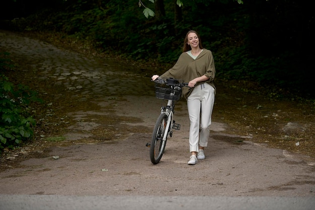 Un retrato de una joven hermosa con una bicicleta en el parque