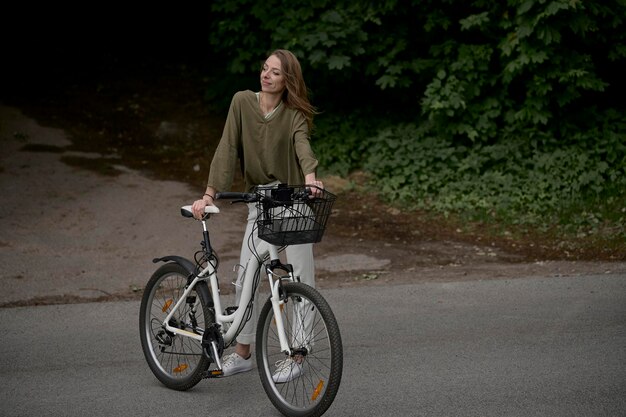 Un retrato de una joven hermosa con una bicicleta en el parque