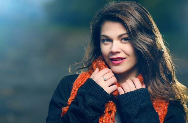 Retrato de una joven hermosa en bufanda de punto rojo, noche al aire libre. la luz azul ilumina el modelo. tonos fríos