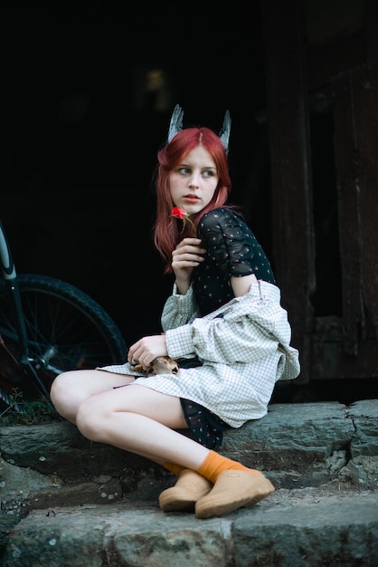 Retrato de una joven hermosa con cabello rojo en la naturaleza con alas de pájaro en la cabeza