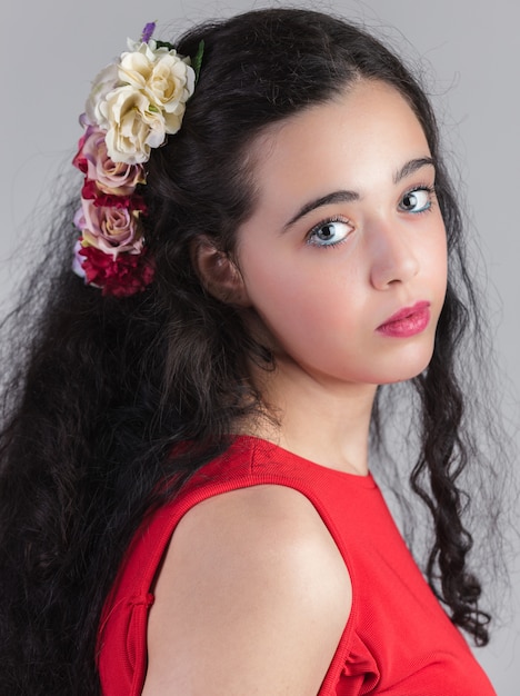 Retrato de joven hermosa con una flor en el pelo.