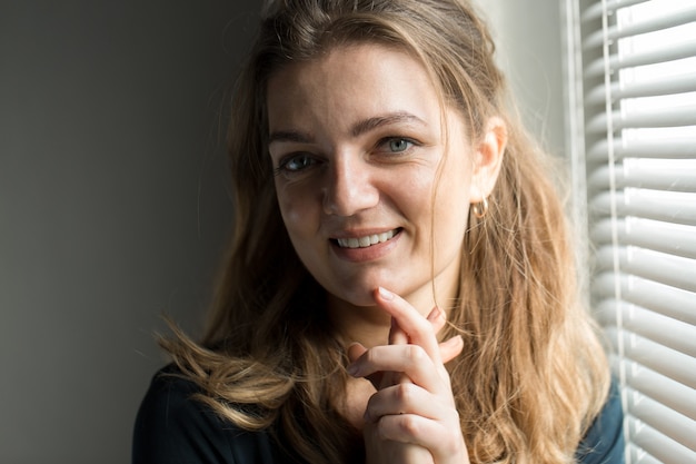 Retrato de una joven hermosa en una habitación sobre un fondo de una pared gris con sombras