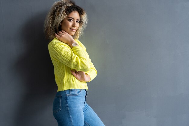 Retrato de joven hermosa linda chica negra alegre sonriendo mirando a cámara sobre fondo gris.