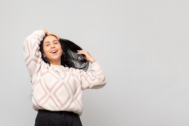 Retrato de una joven hermosa y linda morena con un cálido suéter de invierno de fondo gris claro