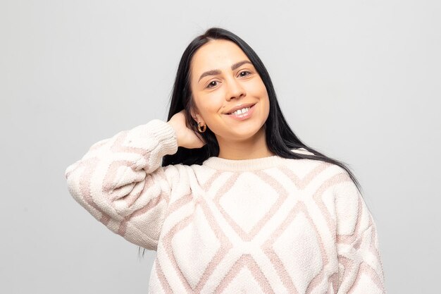 Retrato de una joven hermosa y linda morena con un cálido suéter de invierno de fondo gris claro