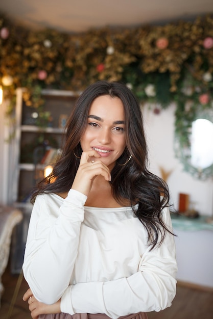 Retrato de una joven y hermosa modelo que se llevó la mano a la boca y sonrió a la cámara Foto de alta calidad