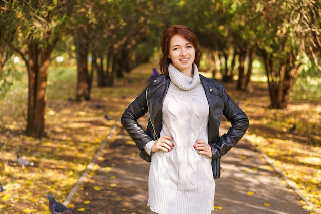 Retrato de una joven hermosa morena con una chaqueta de cuero negro y un suéter de punto con ...