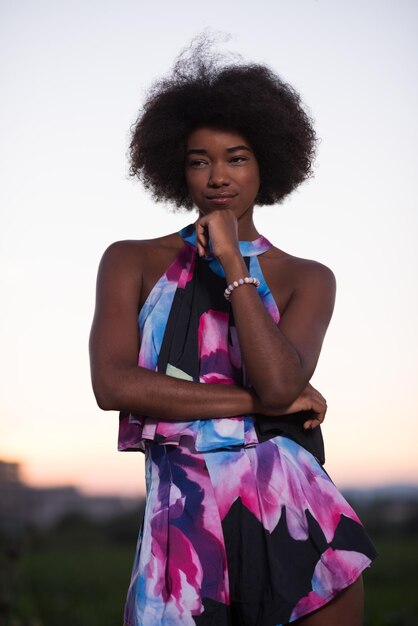 retrato de una joven y hermosa mujer afroamericana en una cálida noche de verano vestida de verano con una sonrisa en la cara