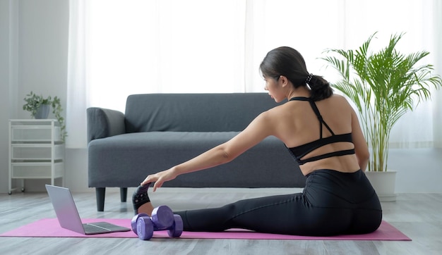 Retrato de joven hermosa mujer asiática estirando ejercicio de calentamiento posición de yoga en casa en la sala de estar Estilo de vida de cuidado de la salud de niña asiática deportiva