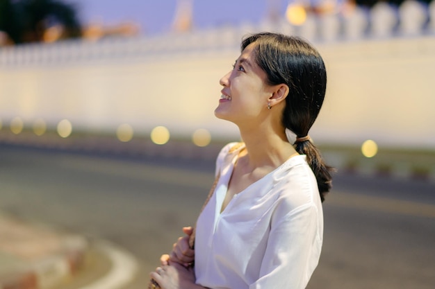 Foto retrato joven hermosa mujer asiática sonriendo mientras viaja en el templo del buda esmeralda o wat phra kaew en el punto de vista del crepúsculo bangkok tailandia