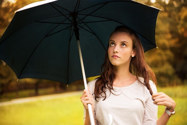 Retrato de joven hermosa mujer caminando en el parque de otoño lluvioso con paraguas.
