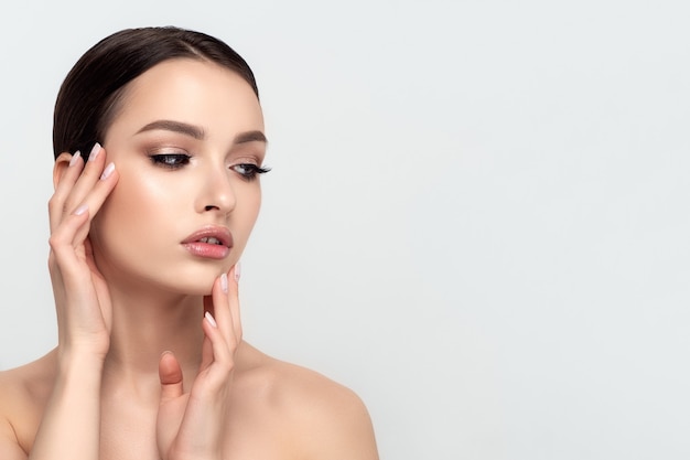 Retrato de joven hermosa mujer caucásica tocando su rostro. Limpieza de la piel, cuidado de la piel, concepto de cosmetología.