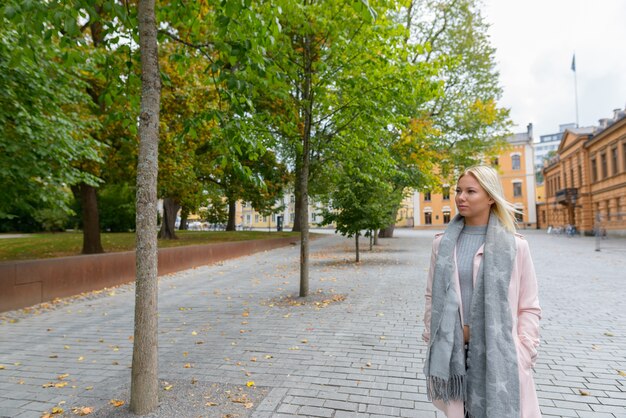 Retrato de joven hermosa mujer escandinava rubia en la tranquila plaza en la ciudad al aire libre