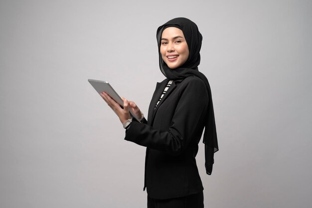 Retrato de una joven y hermosa mujer de negocios musulmana sostiene una tableta sobre un estudio de fondo blanco