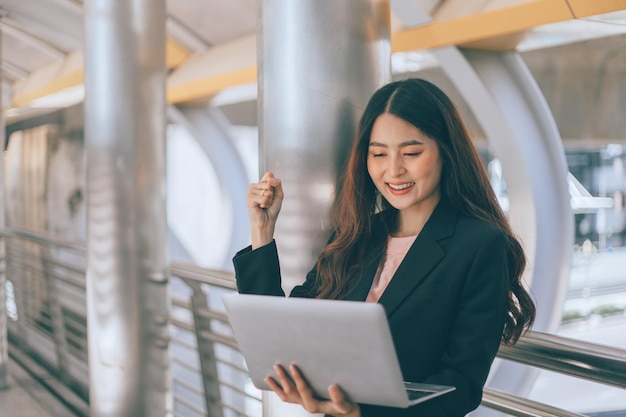 Retrato de una joven y hermosa mujer de negocios parada y usando una laptop