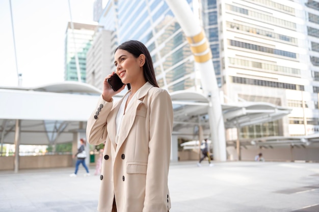 Retrato de una joven y hermosa mujer de negocios que usa un teléfono inteligente en una ciudad moderna