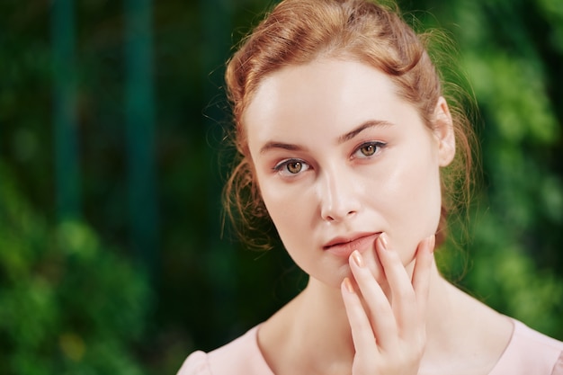 Retrato de joven hermosa mujer pensativa con maquillaje natural mirando a la cámara