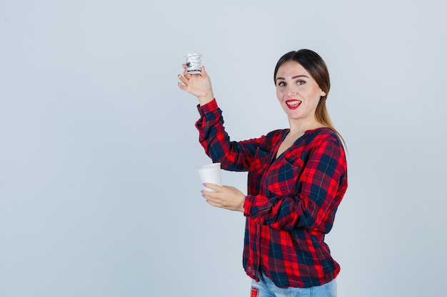 Retrato de joven hermosa mujer posando con gafas de plástico en camisa casual, jeans y mirando alegre vista frontal