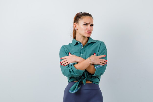 Retrato de joven hermosa mujer sintiendo frío en camisa verde y mirando triste vista frontal