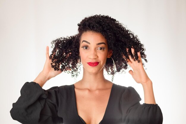 Foto retrato de una joven hermosa mujer sonriente con la mano en el cabello mirando a la cámara