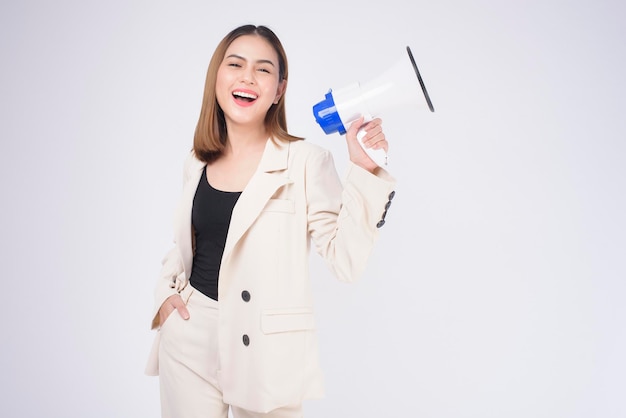 Retrato de joven hermosa mujer sonriente en traje usando megáfono para anunciar sobre estudio aislado de fondo blanco