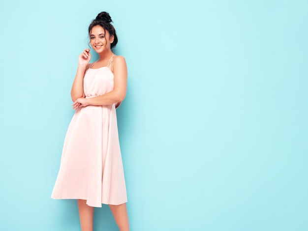 Foto retrato de joven hermosa mujer sonriente en vestido de verano de moda mujer sexy despreocupada posando cerca de la pared azul en el estudio modelo positivo divirtiéndose en el interior alegre y feliz