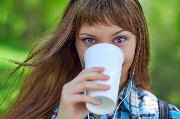 Retrato joven hermosa mujer tomando café en la taza de papel