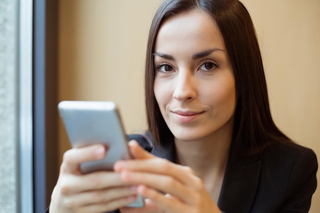 Retrato de joven hermosa mujer trabajando en el teléfono o usando Internet sentado en un café