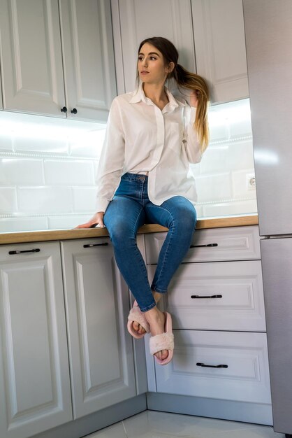 Retrato de joven hermosa posando en la cocina.