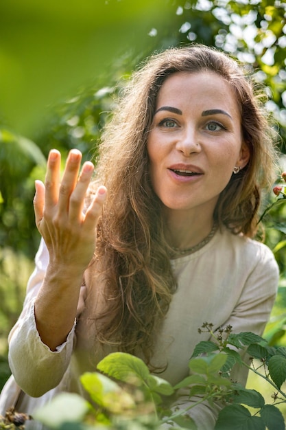 Retrato de joven hermosa recoge moras y frambuesas en el jardín