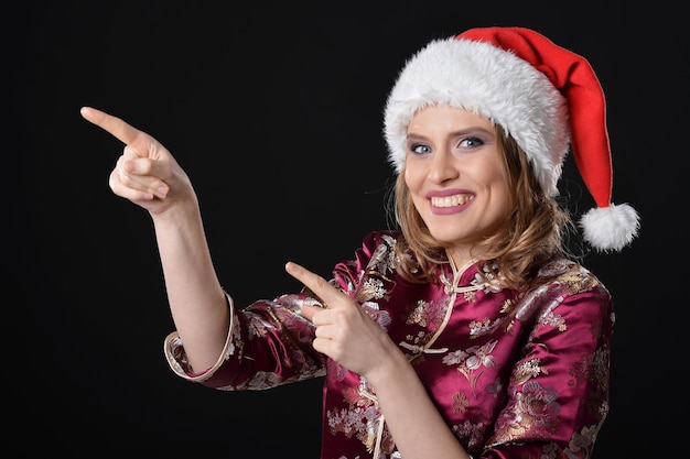 Retrato de joven hermosa con sombrero de Santa posando sobre fondo oscuro